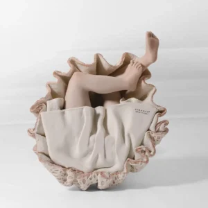 Statua in porcellana di ragazza seduta a terra con abito rosa e bianco in pizzo e due chignon con fiocchi rosa.