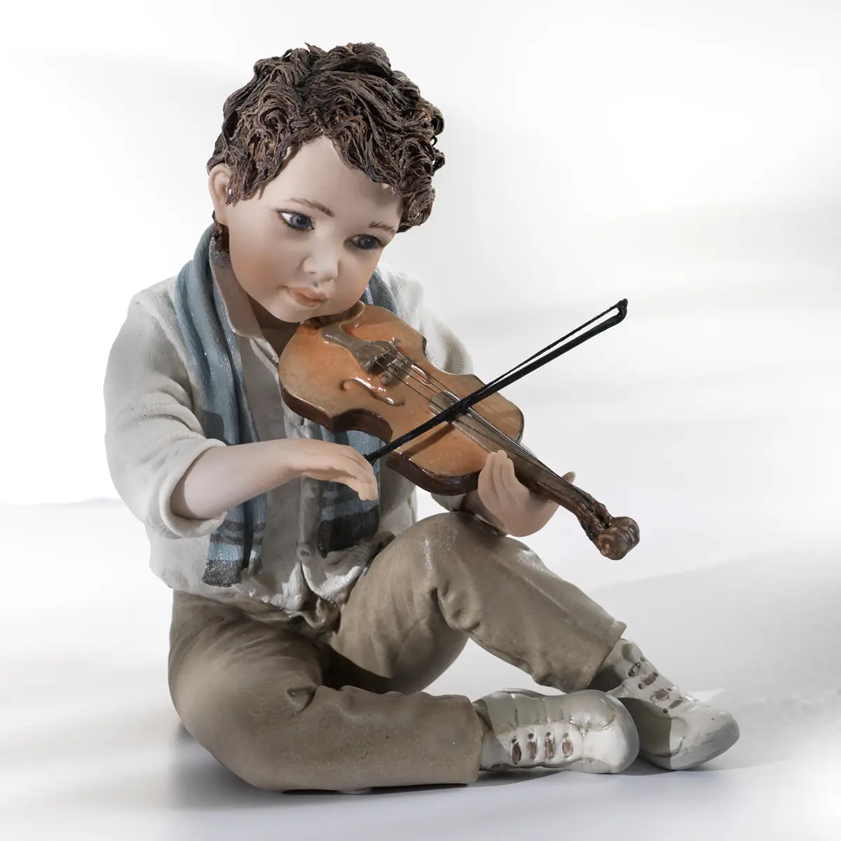 Statua in porcellana di Tamino, ragazzo con camicia azzurrina, pantaloni marroni e sciarpa azzurra che suona un violino