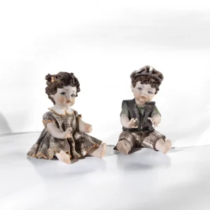 Statue in porcellana Sibania raffiguranti i bimbi Valentina e Tin Tin seduti a terra in abiti primaverili.