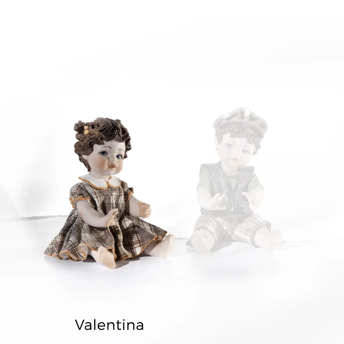 Statua in porcellana di Valentina seduta a terra con Tin Tin, vestito a quadri marrone e bianco e codine alte.