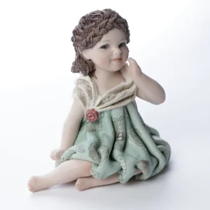 Statua in porcellana di bimba in abito verde menta con fiorellino rosso, bavero in tulle e treccia sulla fronte.